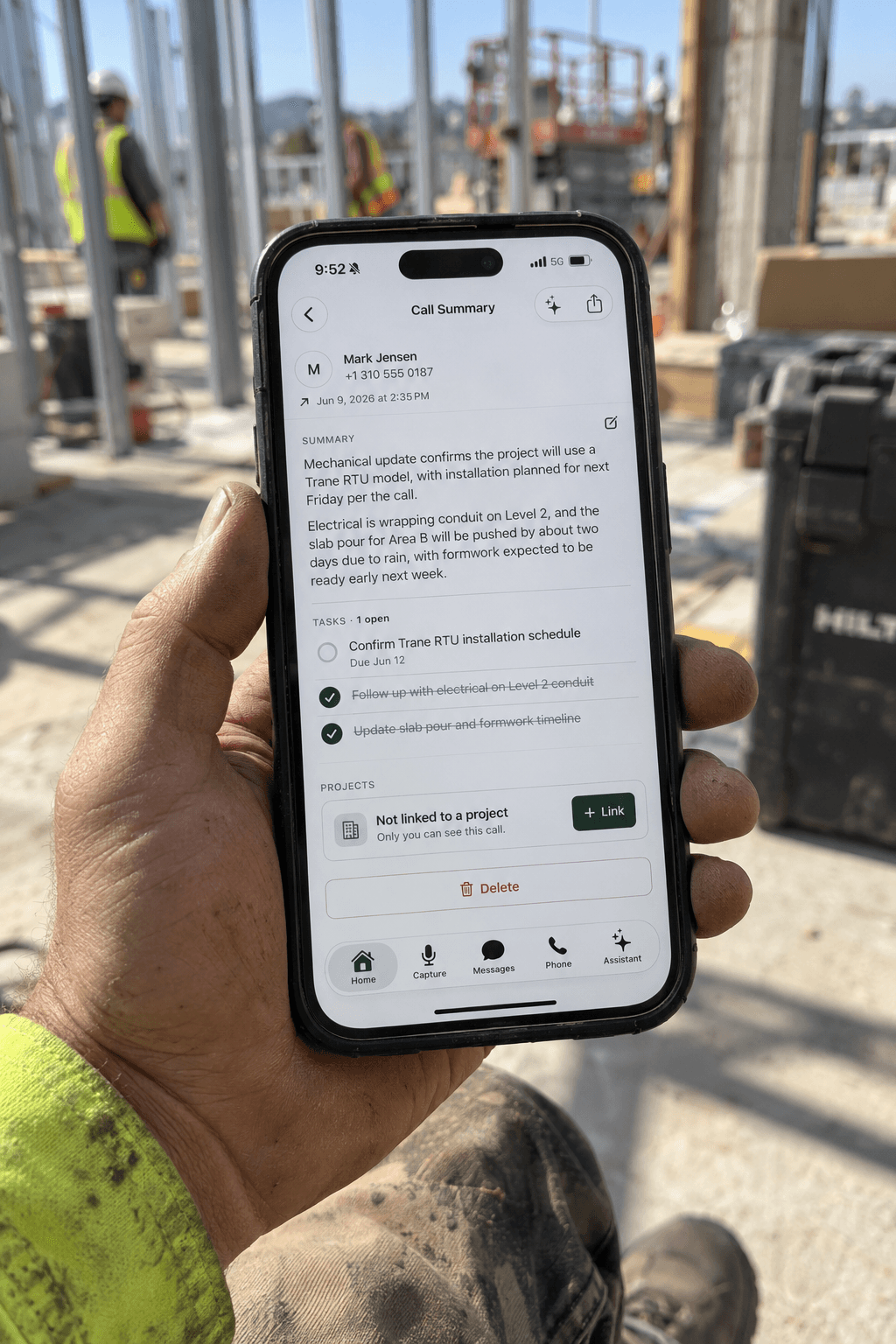 A hand on a jobsite holding a phone showing a Hardline call summary with the call's notes and follow-up tasks